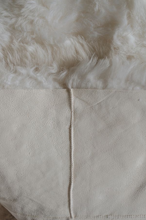 Close-up of the reverse of a white designer sheepskin rug, showing the seams between the square sections