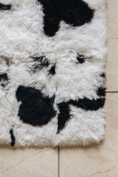 Designer Icelandic Sheepskin rug with natural black patterns on a tiled floor