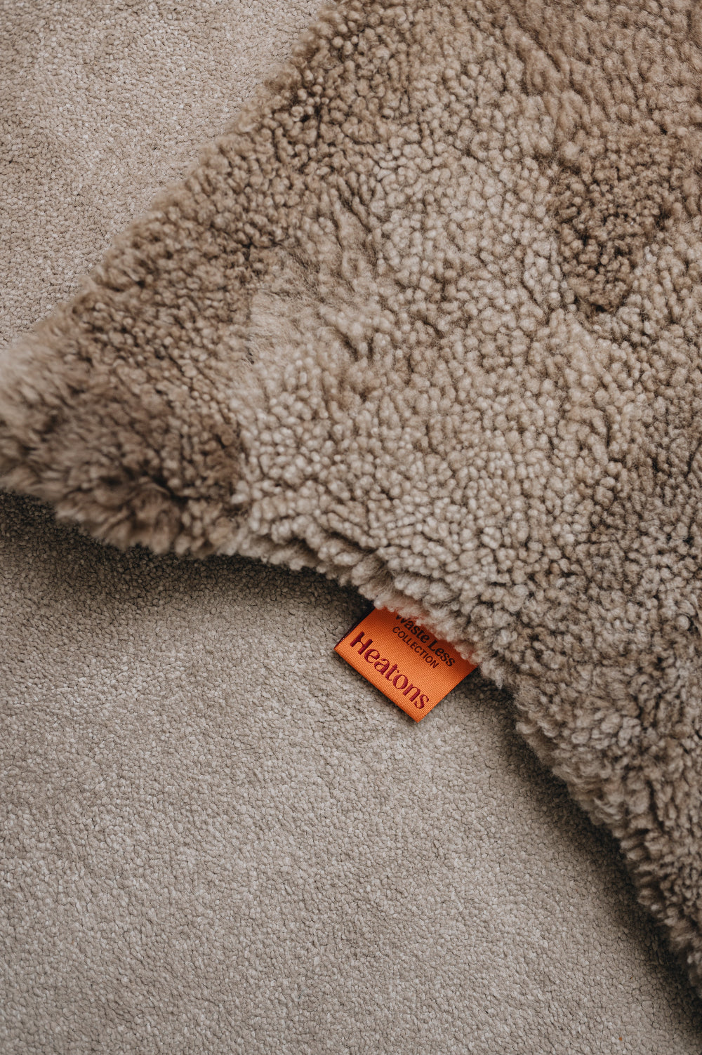 Close-up of a wheat brown sheepskin rug with an orange cotton Heatons brand tag.