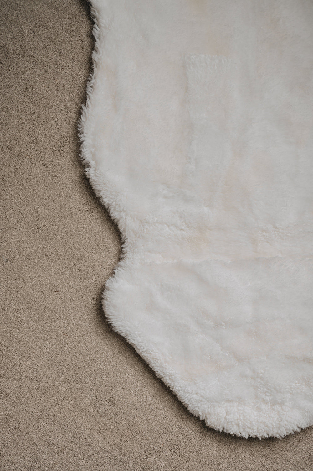 Close-up of a whitel sheepskin rug on a light coloured carpet