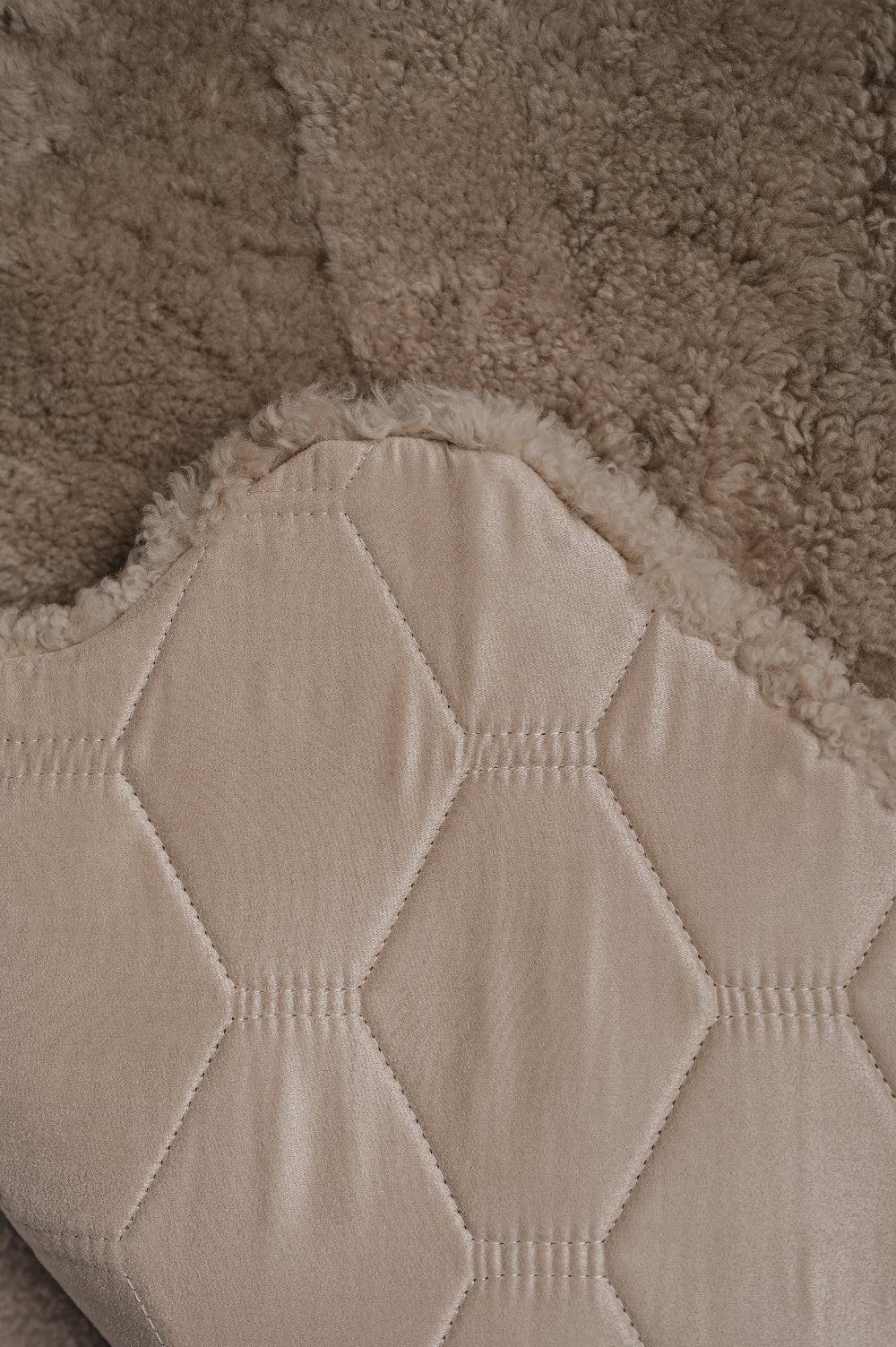 Close-up of a textured beige fabric with a honeycomb pattern on the back / underside of an oatmeal sheepskin rug