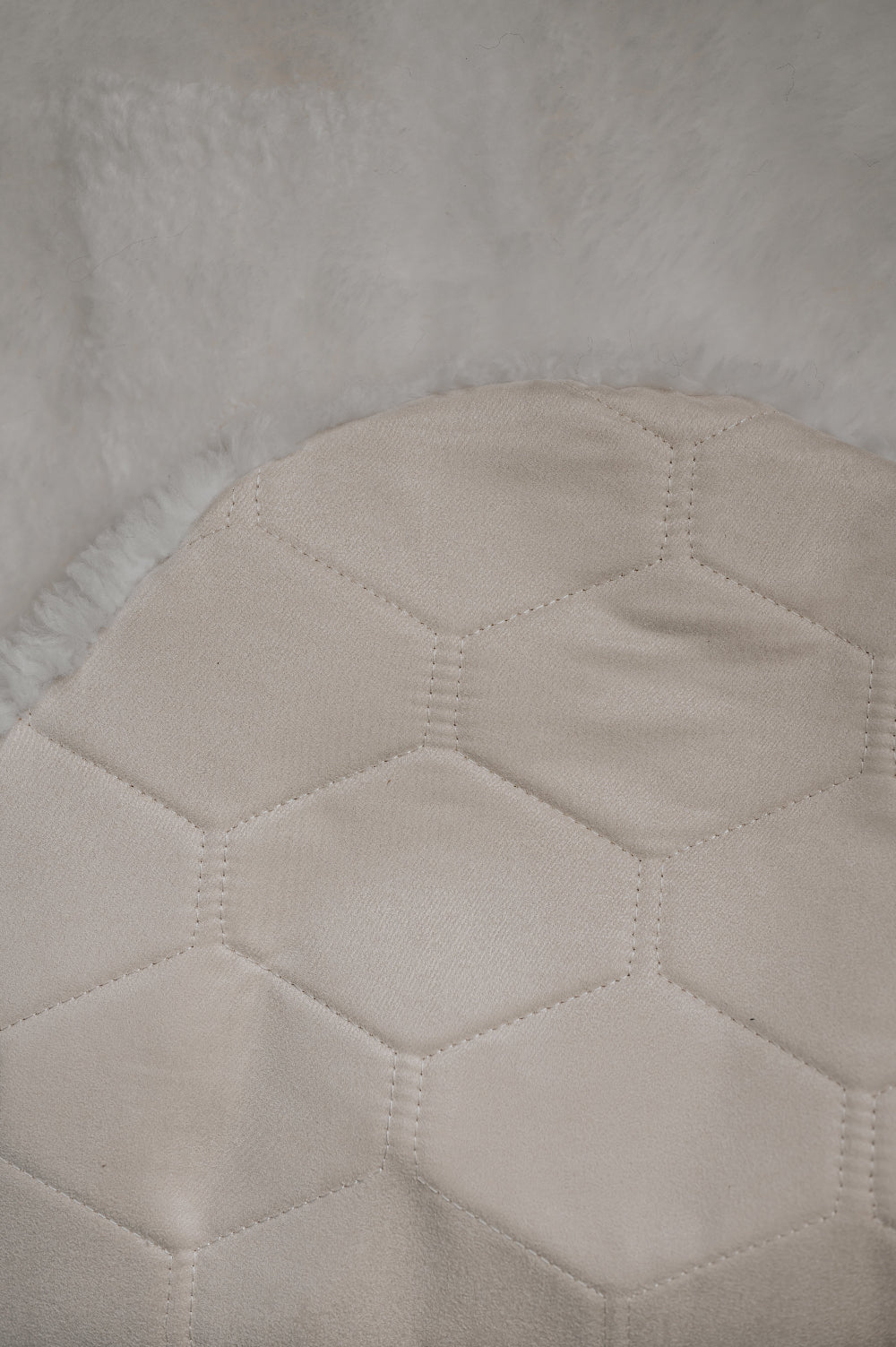 Close-up of a textured light fabric with a honeycomb pattern on the back / underside of a white sheepskin rug