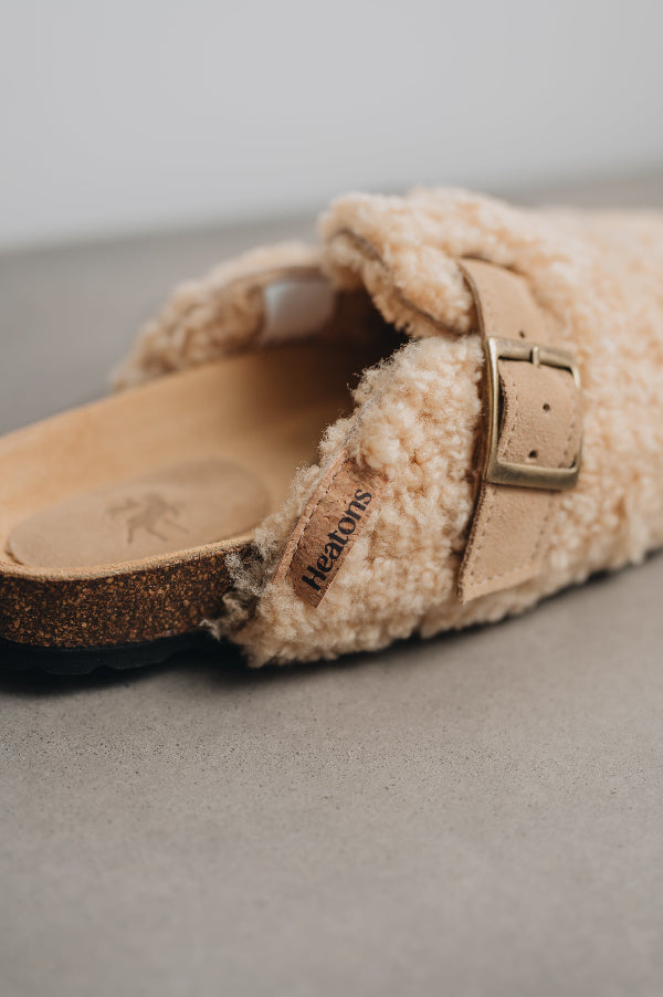 Close up of seren vanilla slide on mules with an adjustable strap and curly sheep skin on both the outside and inside