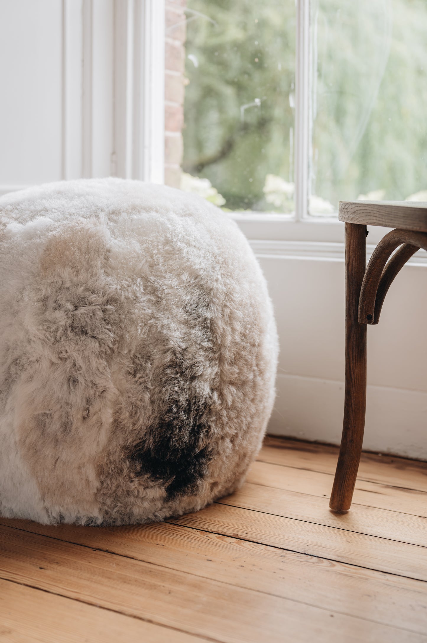 close up of an icelandic sheepskin footstool/pouffe in a melange grey, white and beige colouration