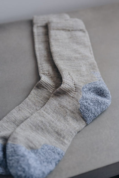 Close up view of beige and blue merino wool socks on a neutral background