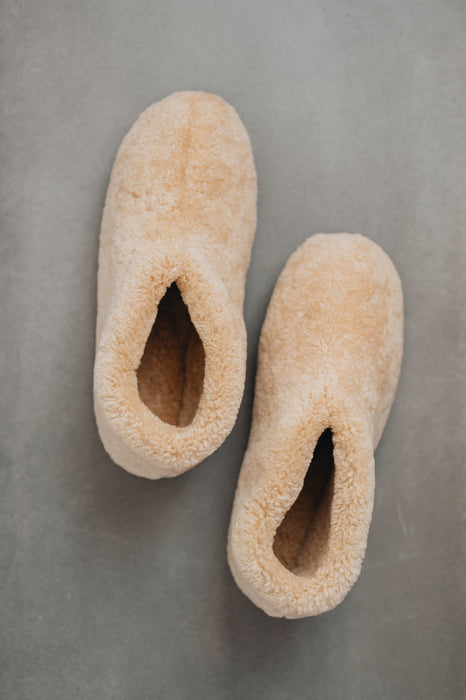 Birds eye view of a camel coloured curly merino sheepskin boot slipper.