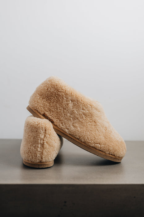 Side view of a camel coloured curly merino sheepskin boot slipper.