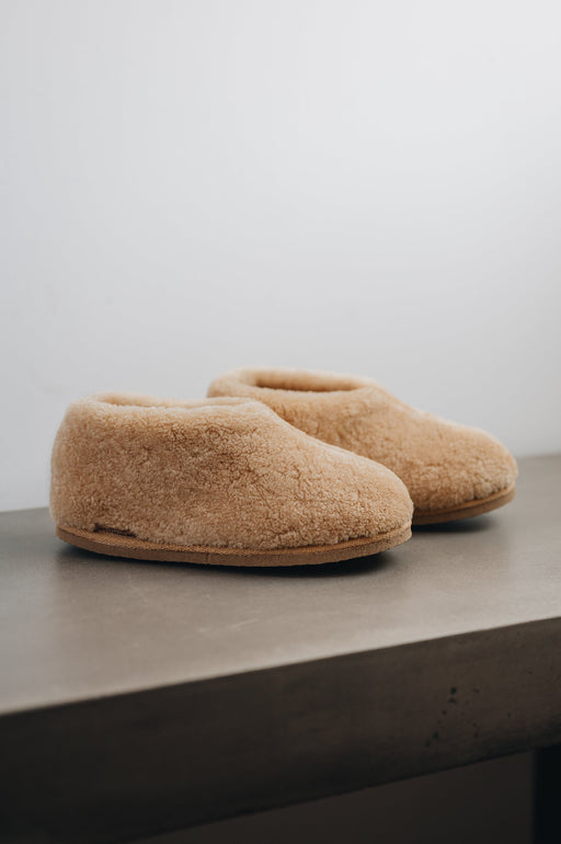 Side view of a camel coloured curly merino sheepskin boot slipper.