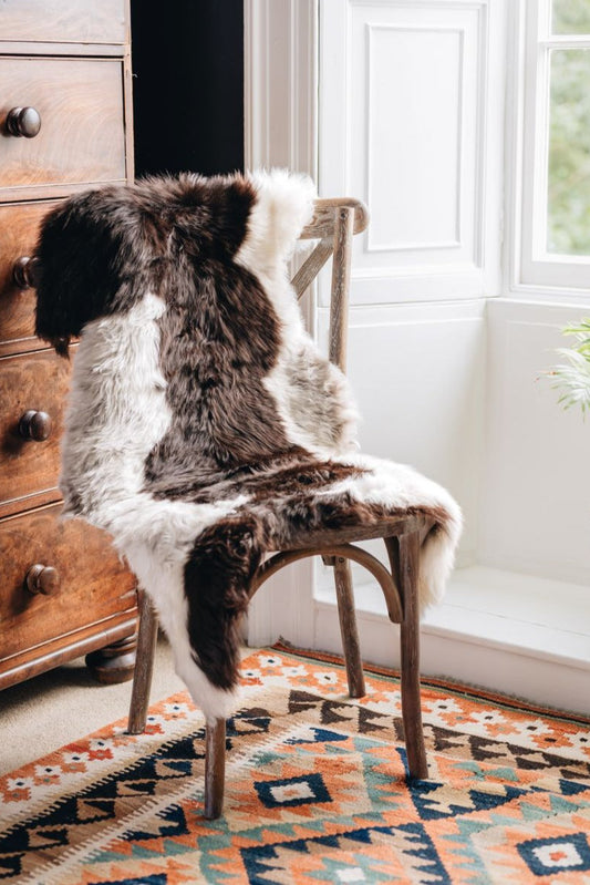 British Jacob rug in Natural white and brown spots draped over a wooden chair