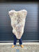 sheepskin rug being held up to show natural markings, an overall cream coloration with a darker brown at the root of the wool