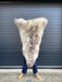sheepskin rug being held up to show natural markings, cream with light brown dappled markings