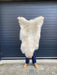 sheepskin rug being held up to show natural colouration, cream and beige mix
