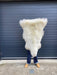 sheepskin rug being held up to show natural markings, mixed cream and beige