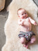 Smiling baby laid on a milk coloured Sheepskin Nursing rug on the floor in a nursery playroom