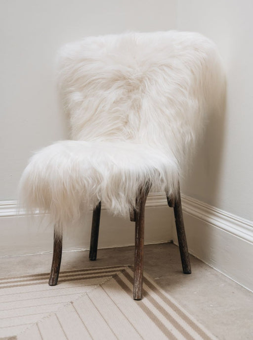 Icelandic Long Wool Sheepskin Rug in White, draped over wooden chair.