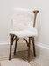 Short Wool Icelandic Sheepskin Rug in white, hung over a wooden chair