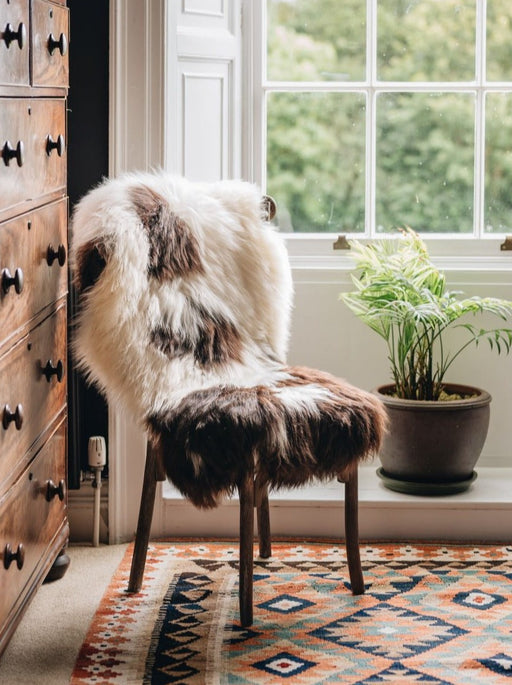 British Jacob rug in Natural white and brown spots draped over a wooden chair