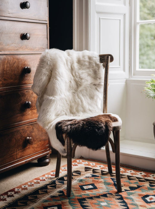 British Jacob rug in Natural white and brown spots draped over a wooden chair