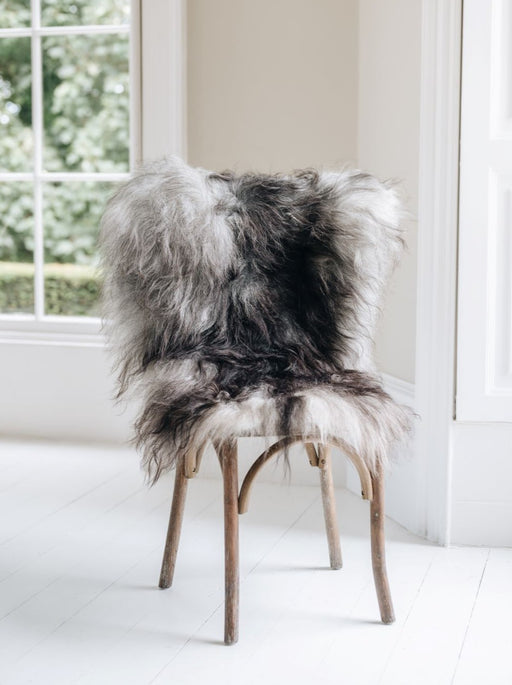 Natural grey undyed Icelandic Sheepskin Rug draped over a wooden chair settled in a window