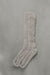 Ribbed beige natural merino wool sock on a light grey background.