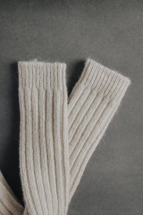 Ribbed natural merino wool sock on a light grey background - detail of ribbed sock neck