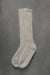 Ribbed beige natural merino wool sock on a light grey background.