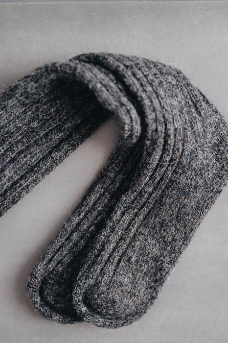 Ribbed brown natural merino wool sock on a light grey background - detail of ribbed sock and toe post
