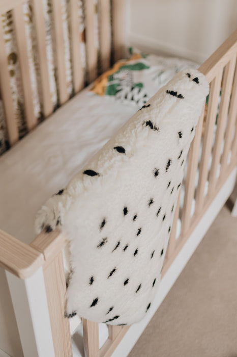 Sheepskin Nursing rug in Ivory Polka Dot draped over a cot in a nursery - downwards close up view