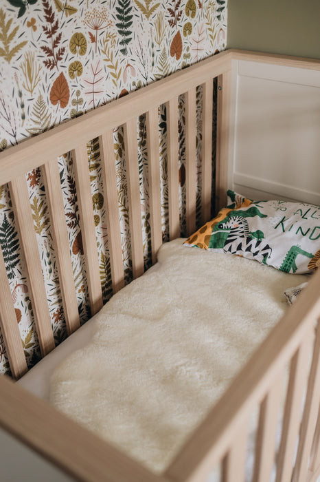 Milk coloured Sheepskin Nursing rug laid in a cot in a young child's nursery