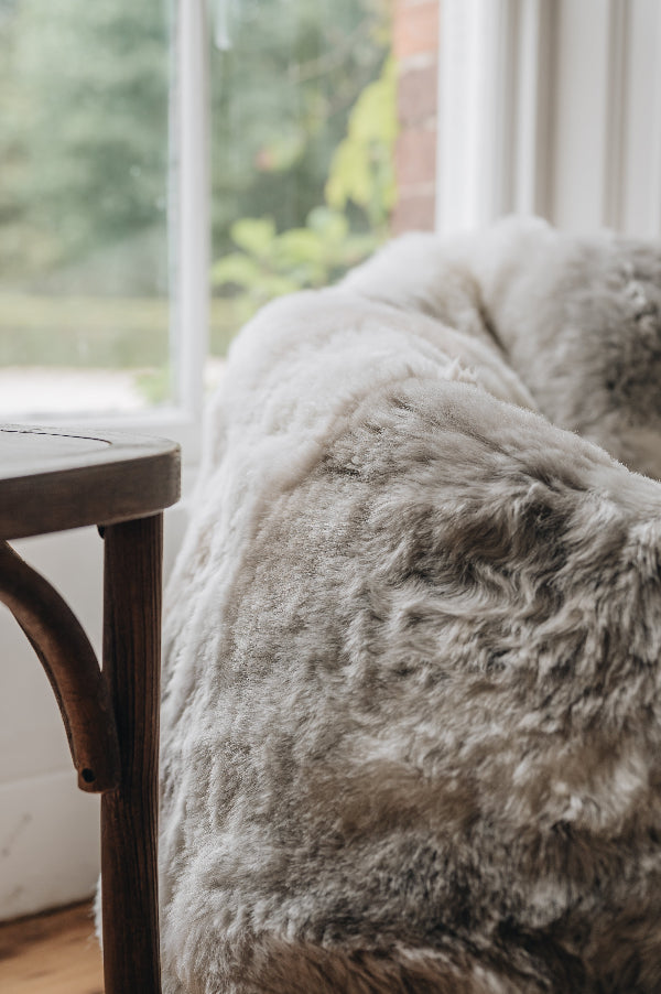 Close-up of a natural melange bean bag next to a wooden chair with a blurred background