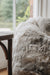 Close-up of a natural melange bean bag next to a wooden chair with a blurred background
