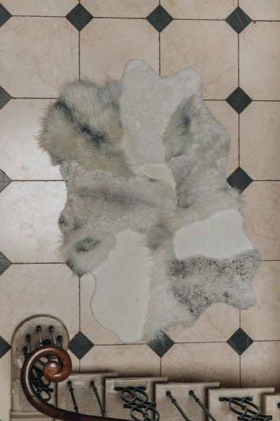 Multilayer designer sheepskin rug in natural melange tones and mixed lengths on a tiled floor 