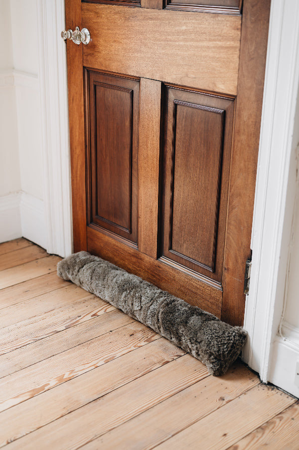 Wooden door with a wheat brown draught excluder on a wooden floor