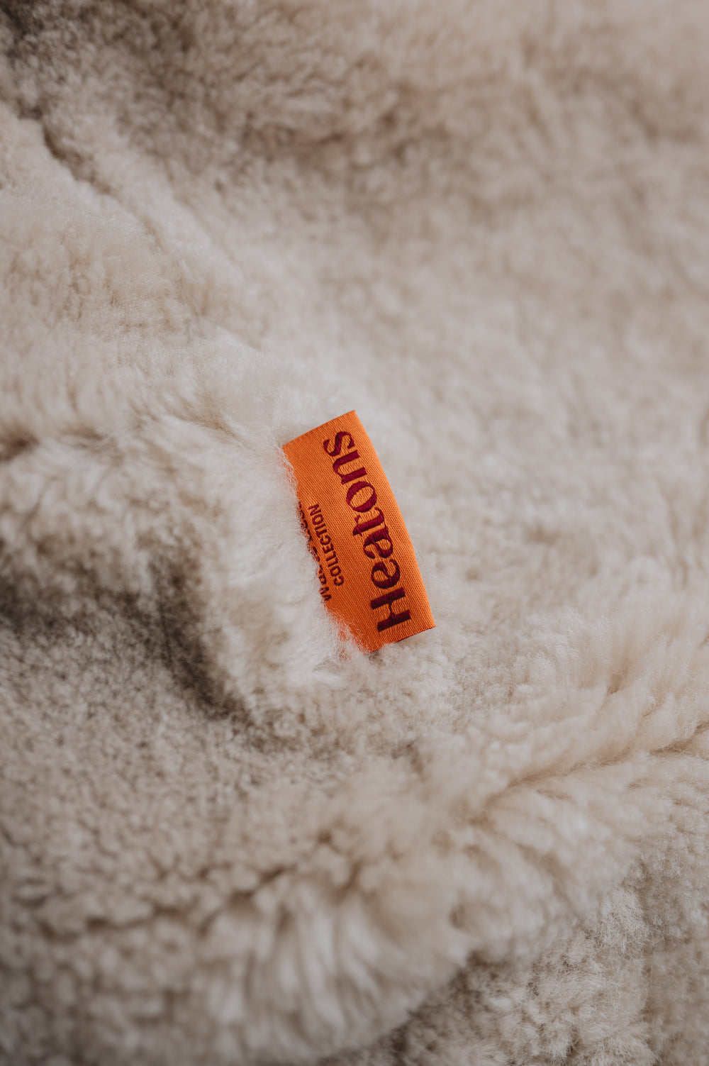 Orange cotton label with 'Heatons' branding on an oatmeal sheepskin beanbag.