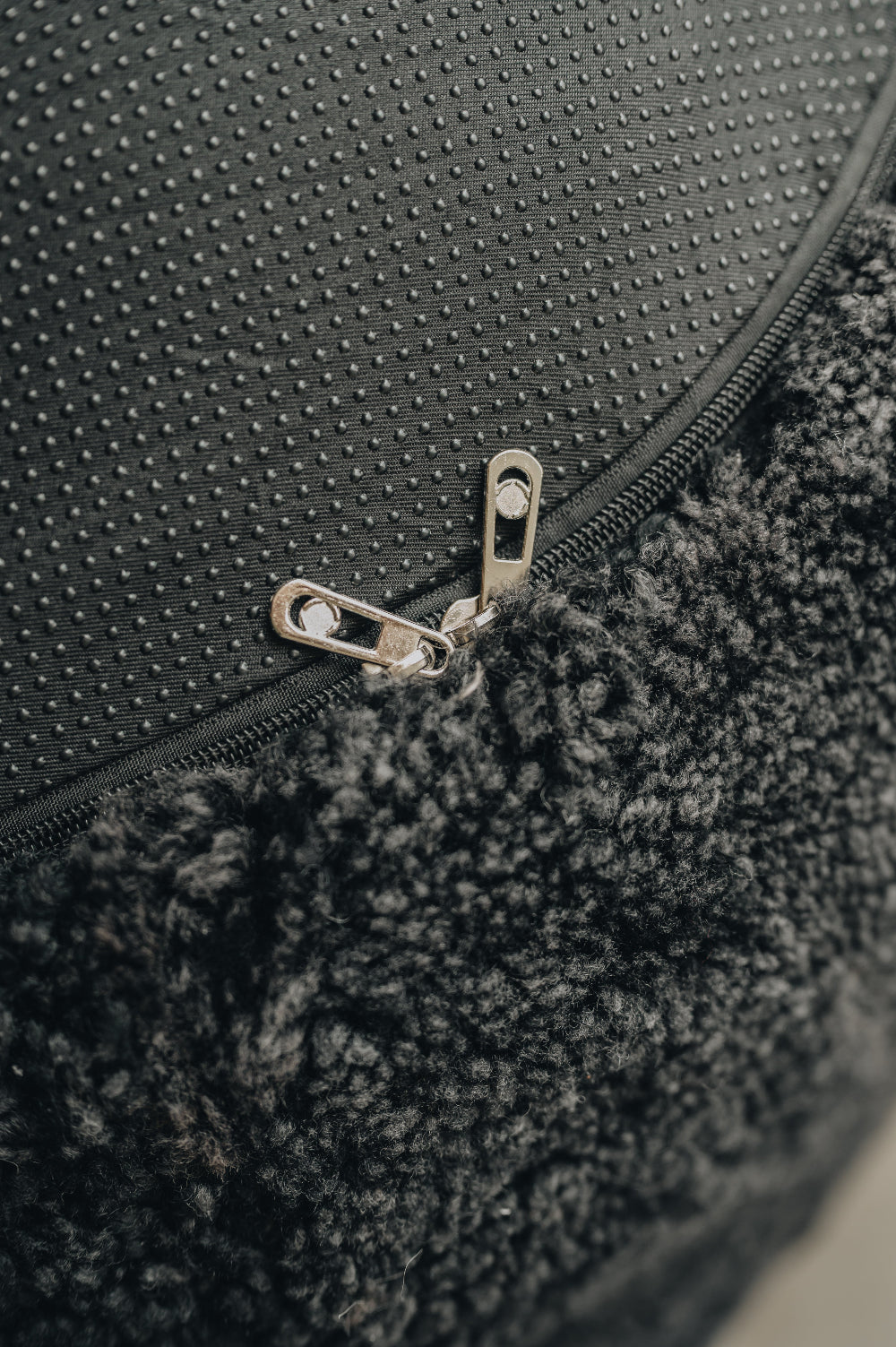 Close-up of a textured fabric bottom of a black sheepskin bean bag with a zipper