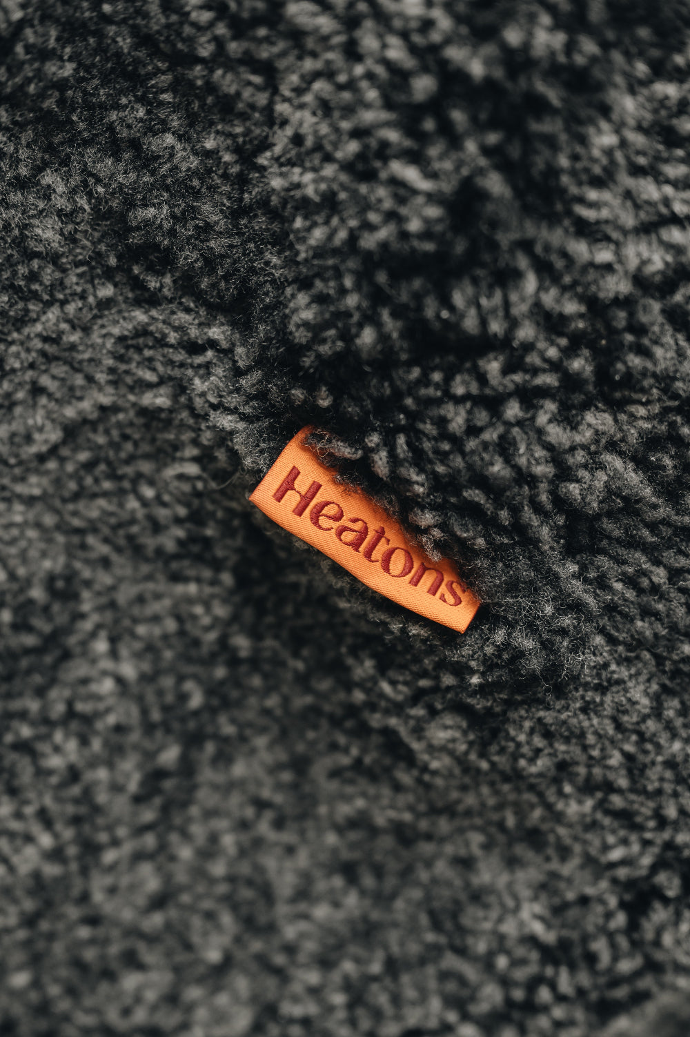 Orange cotton label with 'Heatons' branding on a black smoke sheepskin beanbag.