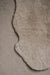 Close-up of an oatmeal sheepskin rug on a similar coloured carpet