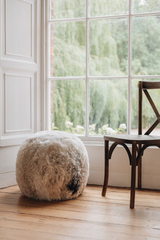an Icelandic sheepskin footstool/pouffe in a melange colouration, grey and brown mixed tones in a natural pattern