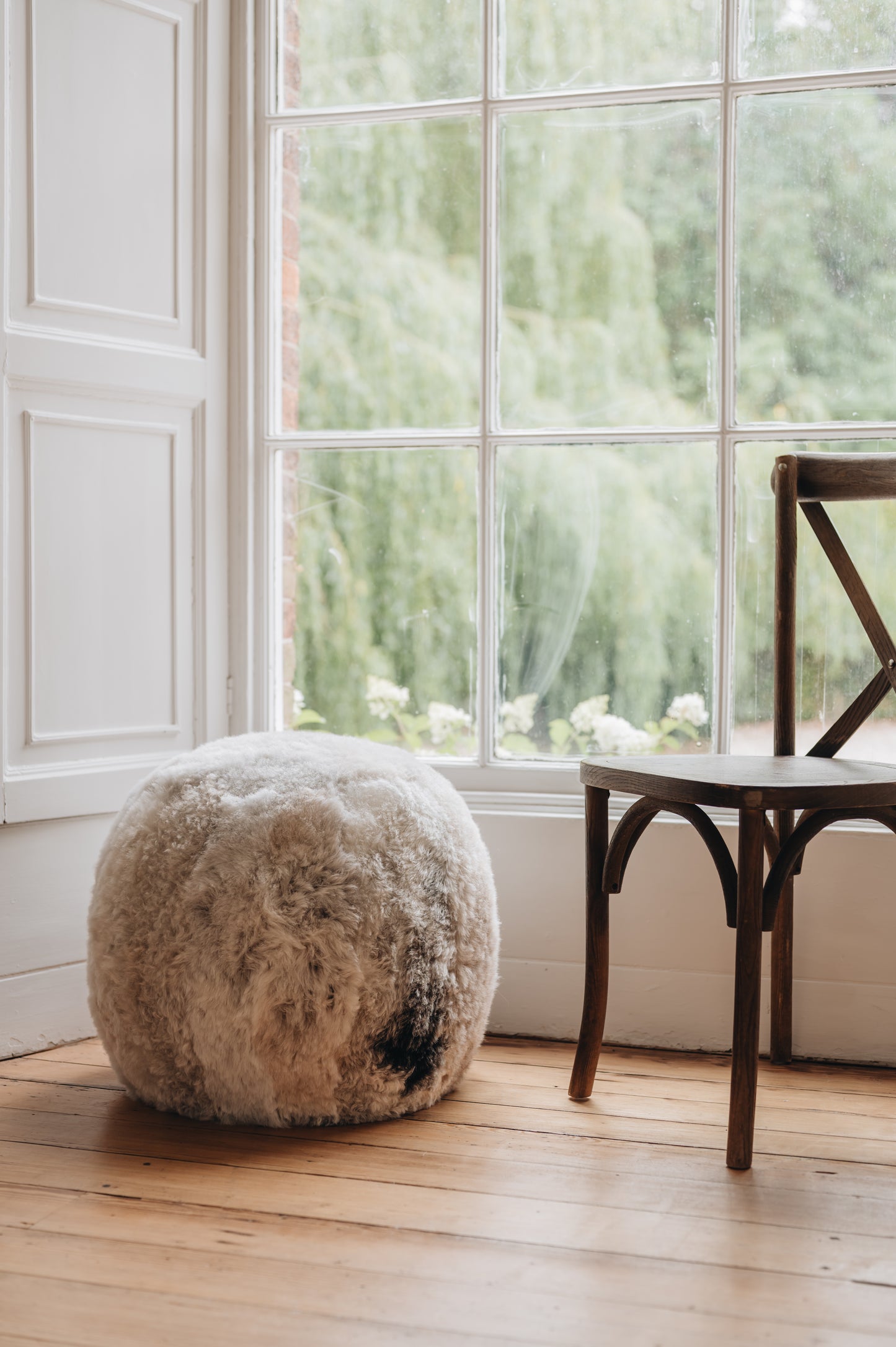 an Icelandic sheepskin footstool/pouffe in a melange colouration, grey and brown mixed tones in a natural pattern