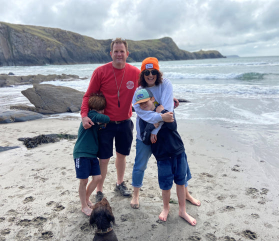 Picture of Westmorland Family. Shows the owners Dom and Tim, with their two children, Huw and Gryff at the beach. Their dog Mali is at the front.