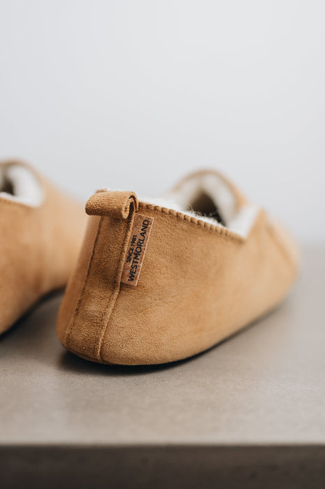 Rear view of Grace, a light soft-soled sheepskin slipper showing the detail of the suede tag and label.