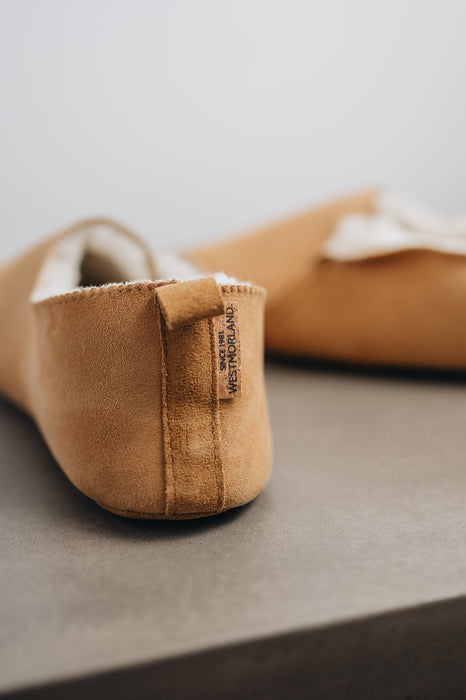 Rear view of Grace, a light soft-soled sheepskin slipper showing the detail of the suede tag and label.
