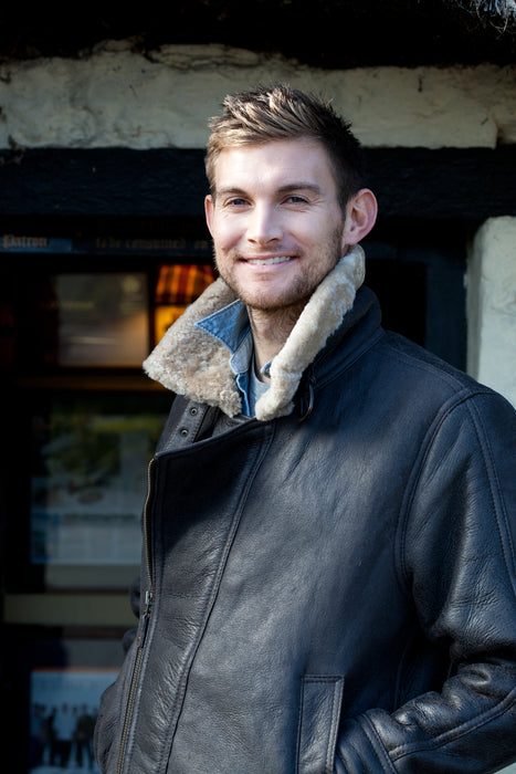 Men's Sheepskin and Leather Blenheim Chocolate Aviator Jacket. Male model wears jacket, undoing the front zip.