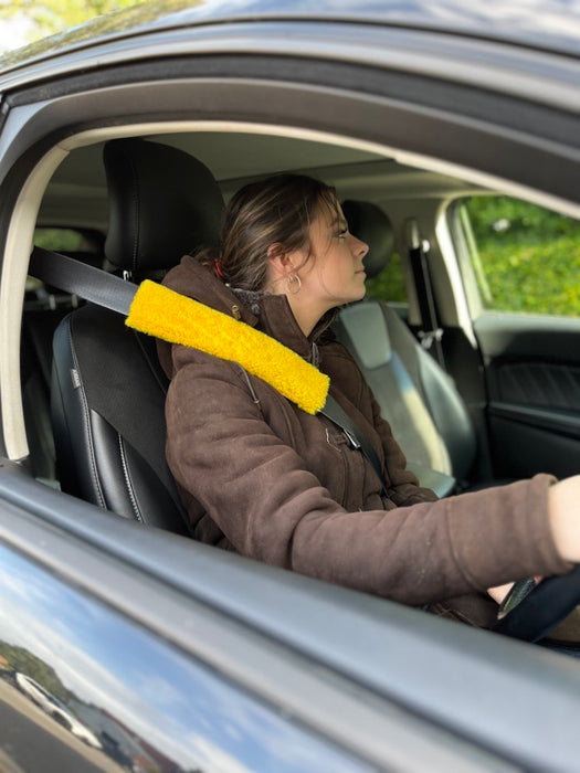 Young woman driving  a car wearing a seatbelt with a yellow sheepskin car seat cover