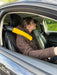 Young woman driving  a car wearing a seatbelt with a yellow sheepskin car seat cover