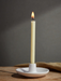 Inspiritus single candle burning in a white holder on a wooden table