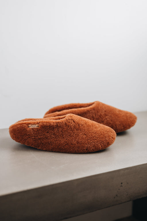 Side view of Curly merino sheepskin slip on slipper with curls on the outside and inside in a rich, warm rust colour.