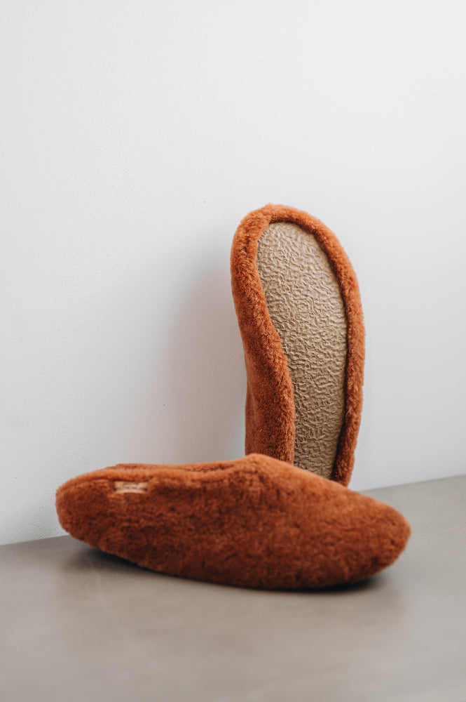 Curly merino sheepskin slip on slipper with curls on the outside and inside in a rich, warm rust colour. Slipper sole showing.