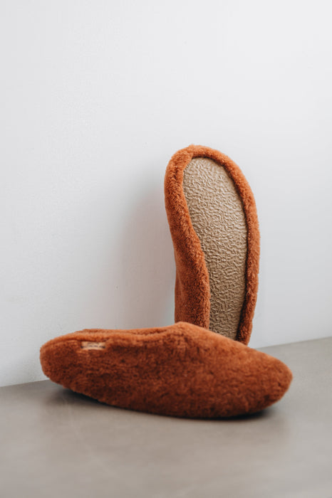 Curly merino sheepskin slip on slipper with curls on the outside and inside in a rich, warm rust colour. Slipper sole showing.