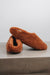 Side view of curly merino sheepskin slip on slipper with curls on the outside and inside in a rich, warm rust colour.